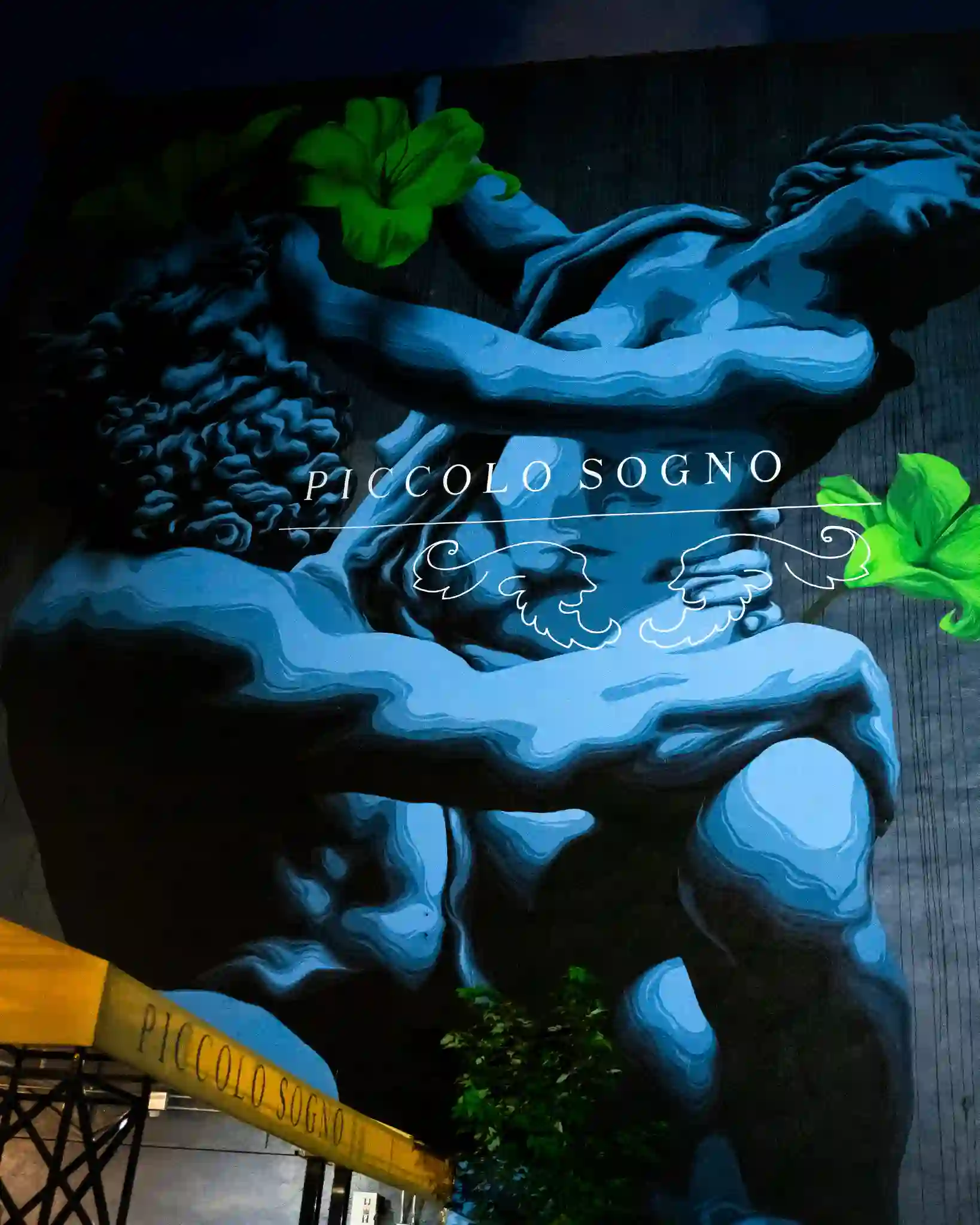 Piccolo Sogno mural with its name painted across a classical sculpture