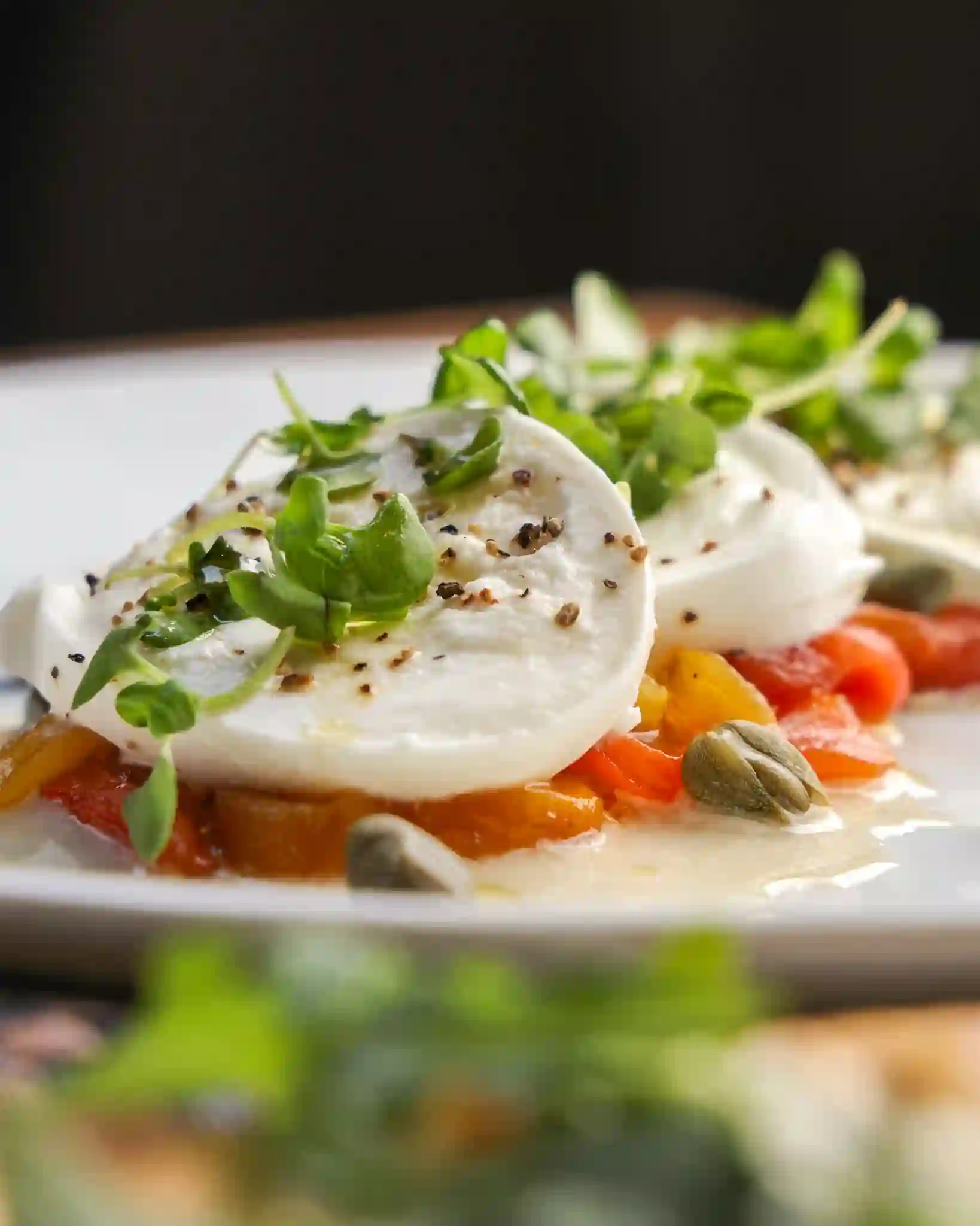 Fresh mozzarella over roasted peppers and capers